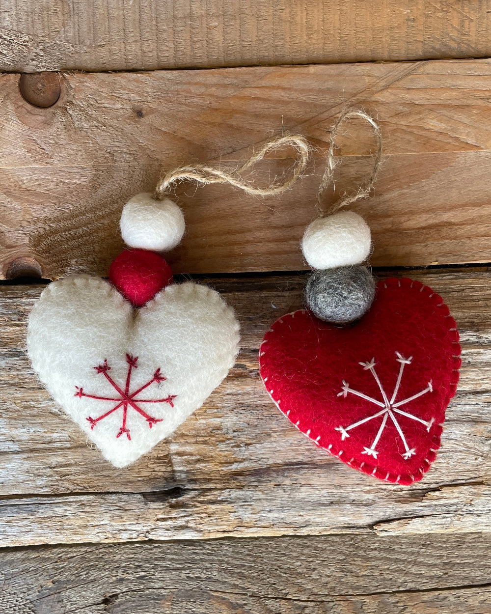 Two heart-shaped decorations with snowflake patterns on a wooden surface
