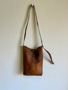 Brown leather bag with a strap on a white background