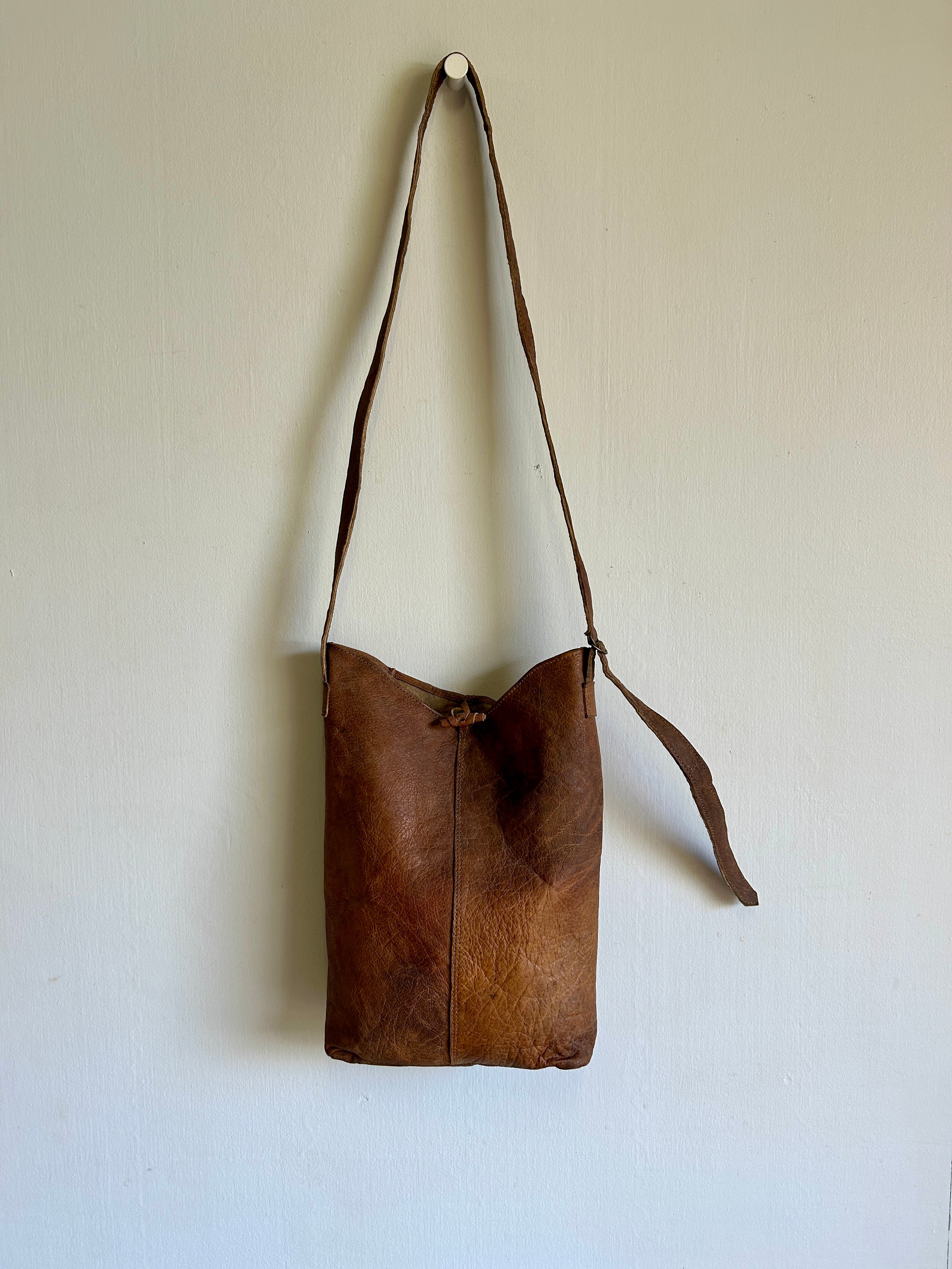 Brown leather bag with a strap on a white background