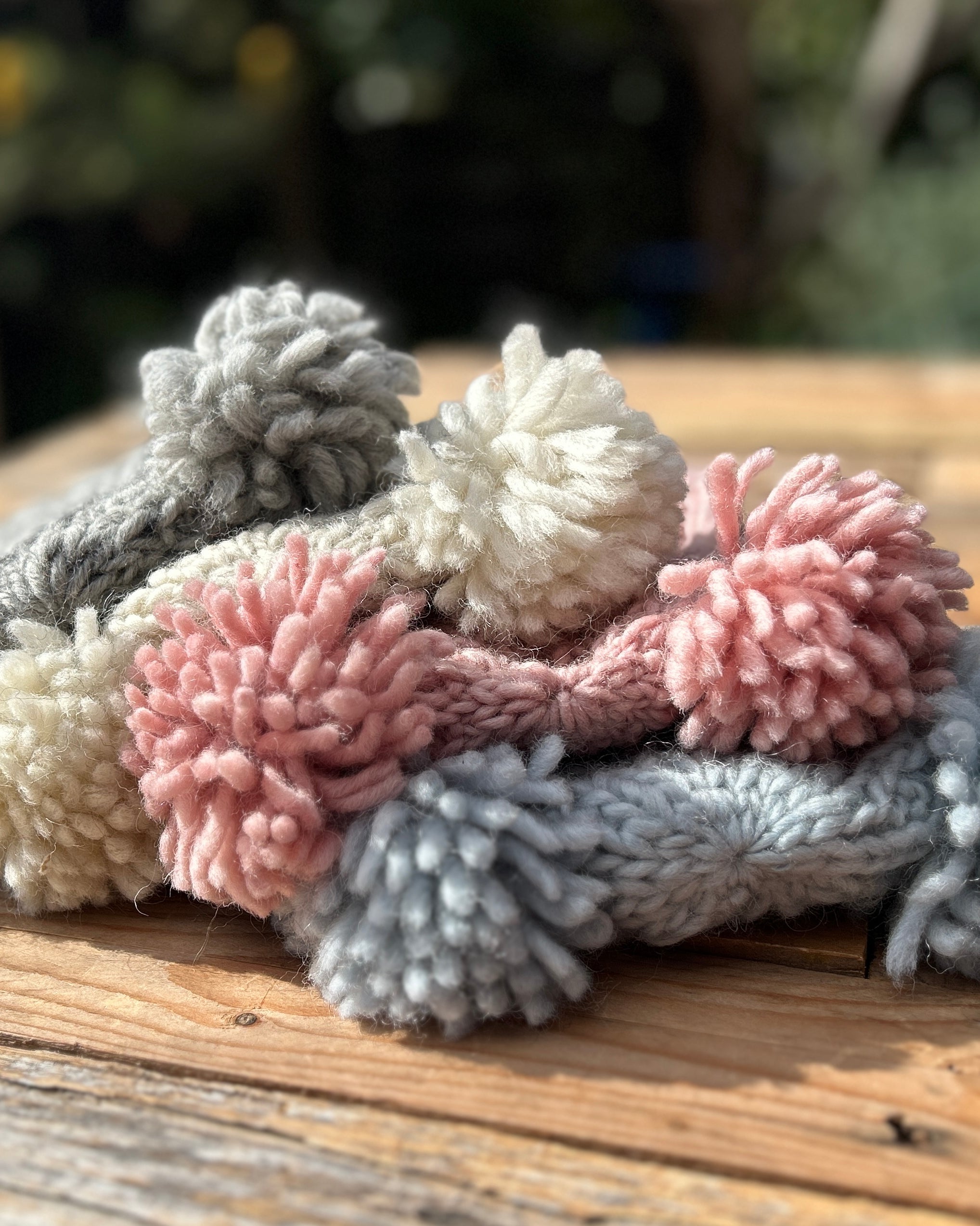 Stack of beanies on a wooden surface with a blurred natural background