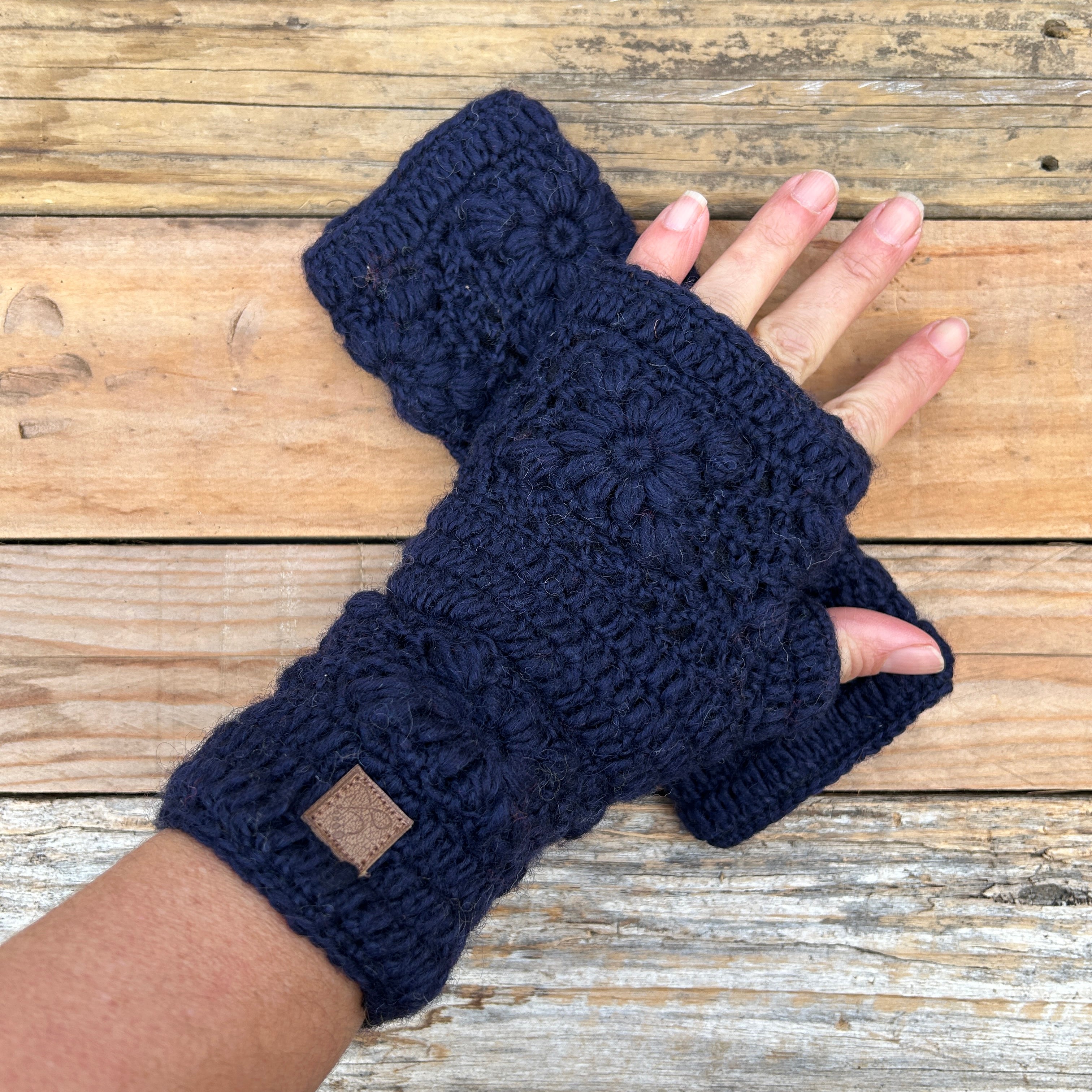 Navy blue knitted fingerless gloves on a wooden surface