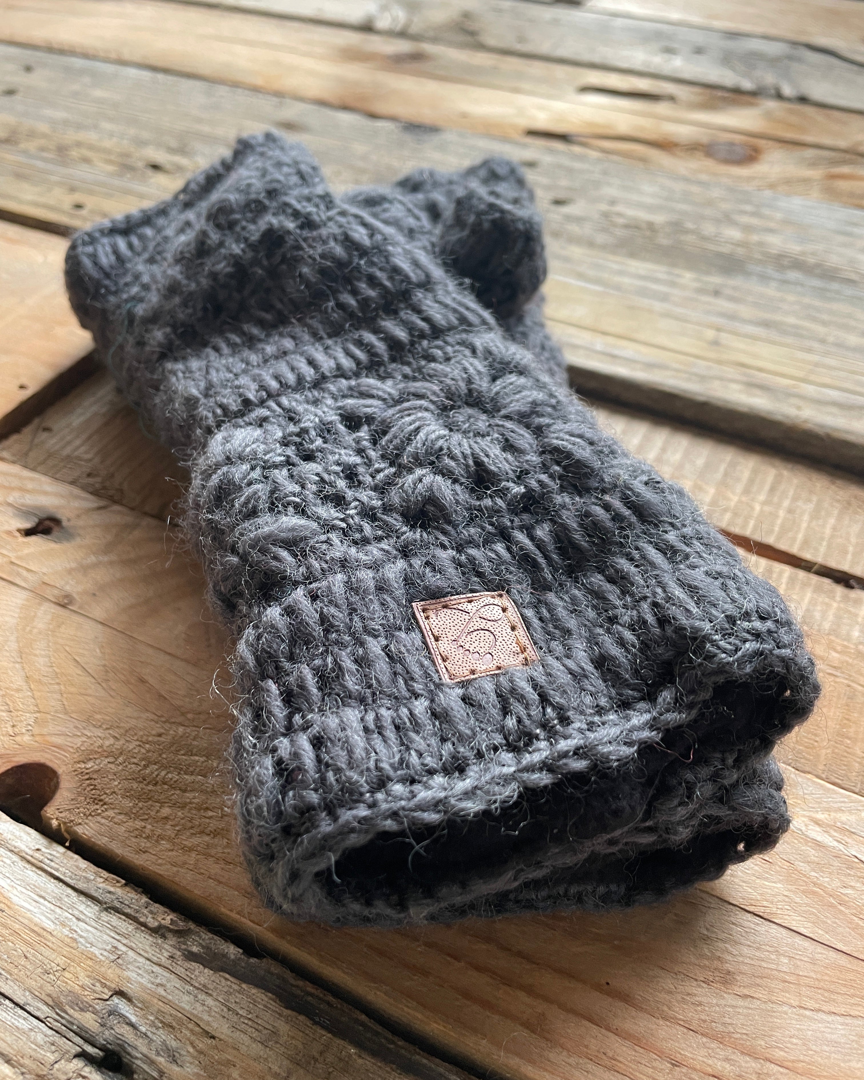 Gray crochet wristwarmer on a wooden surface