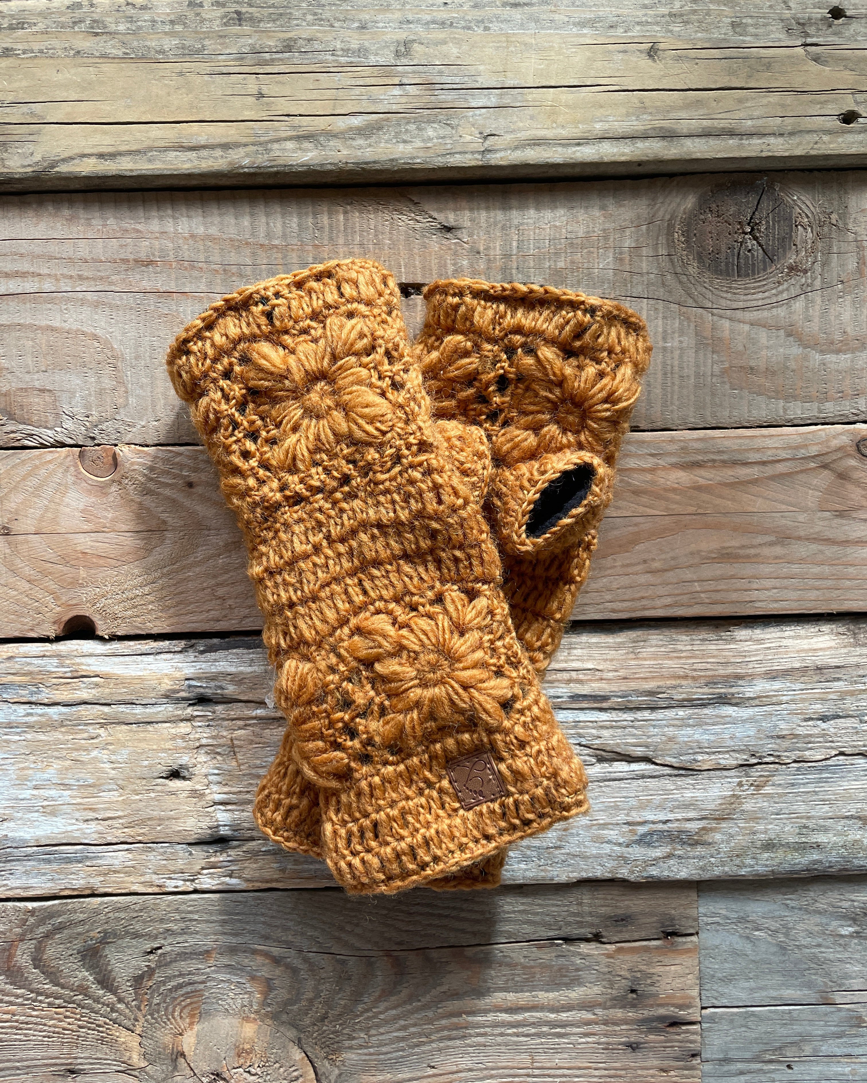 Pair of brown crochet wristwarmers on a wooden surface