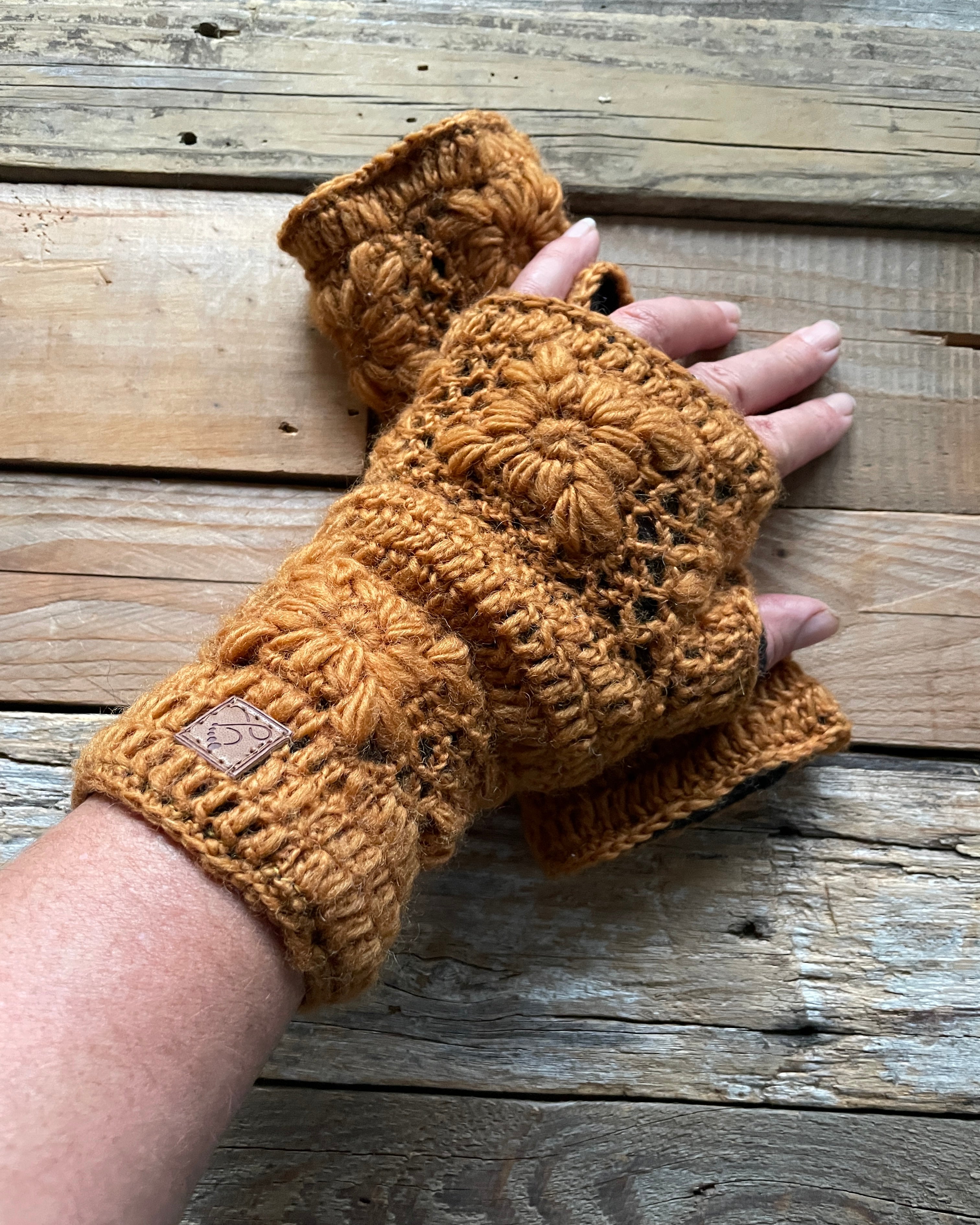 caramel brown crochet fingerless gloves on a wooden surface