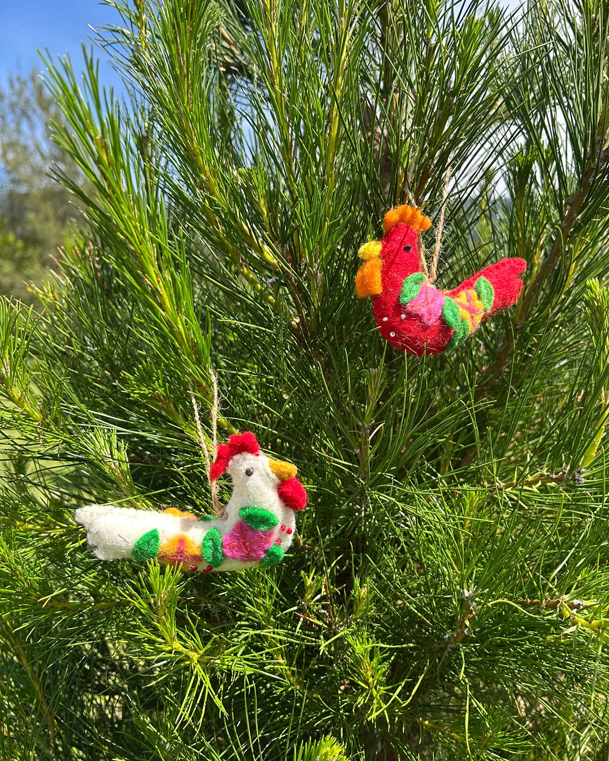 Colorful rooster ornaments hanging on a tree branch
