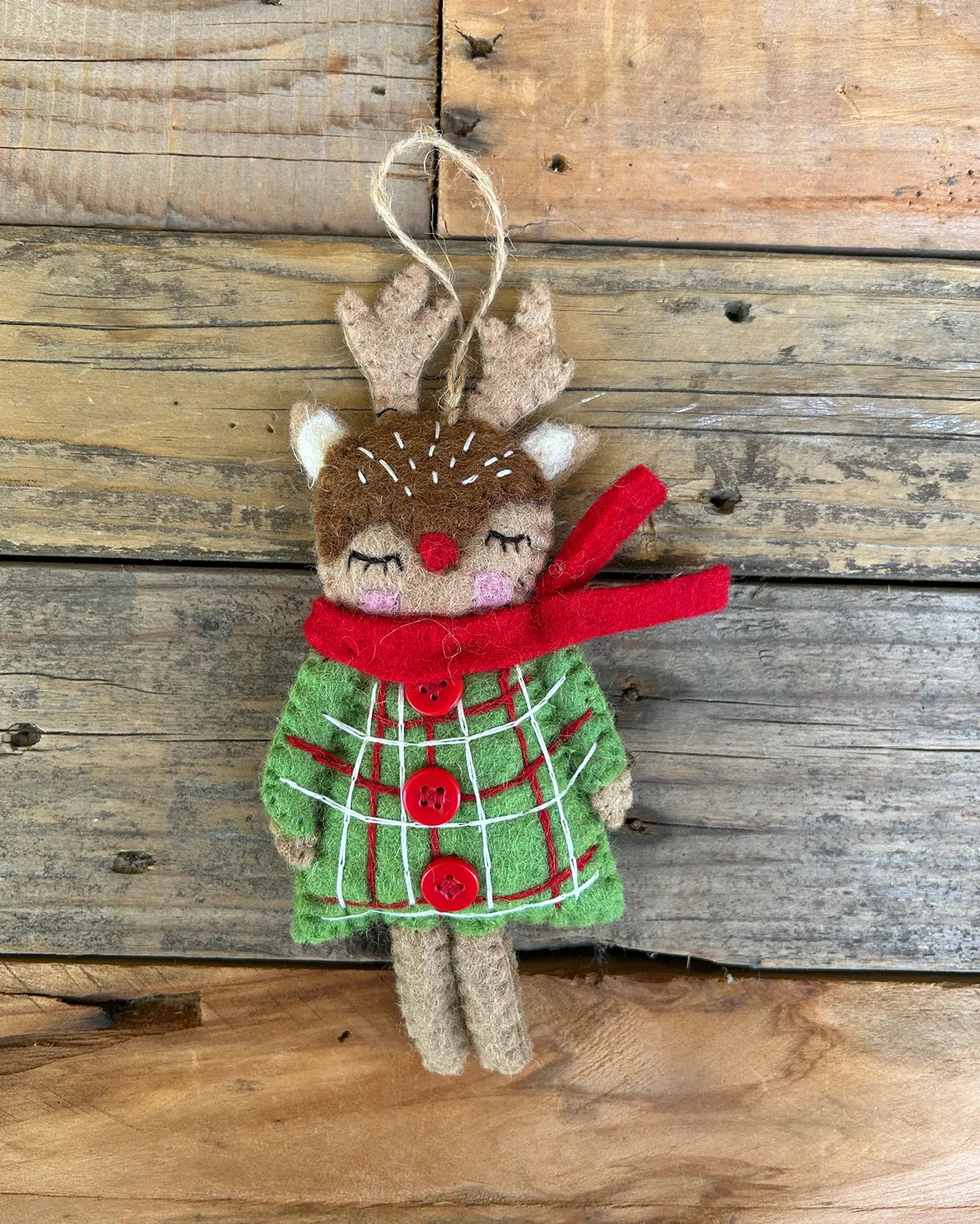 Felt reindeer ornament with a red scarf and green plaid dress on a wooden background