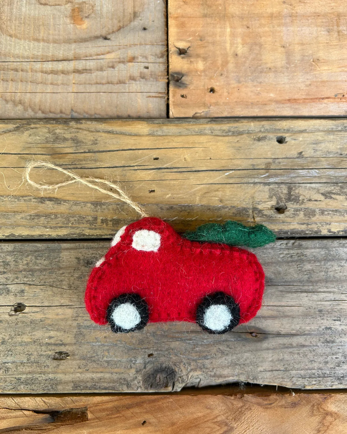 Red felt car ornament with christmas tree on a wooden surface
