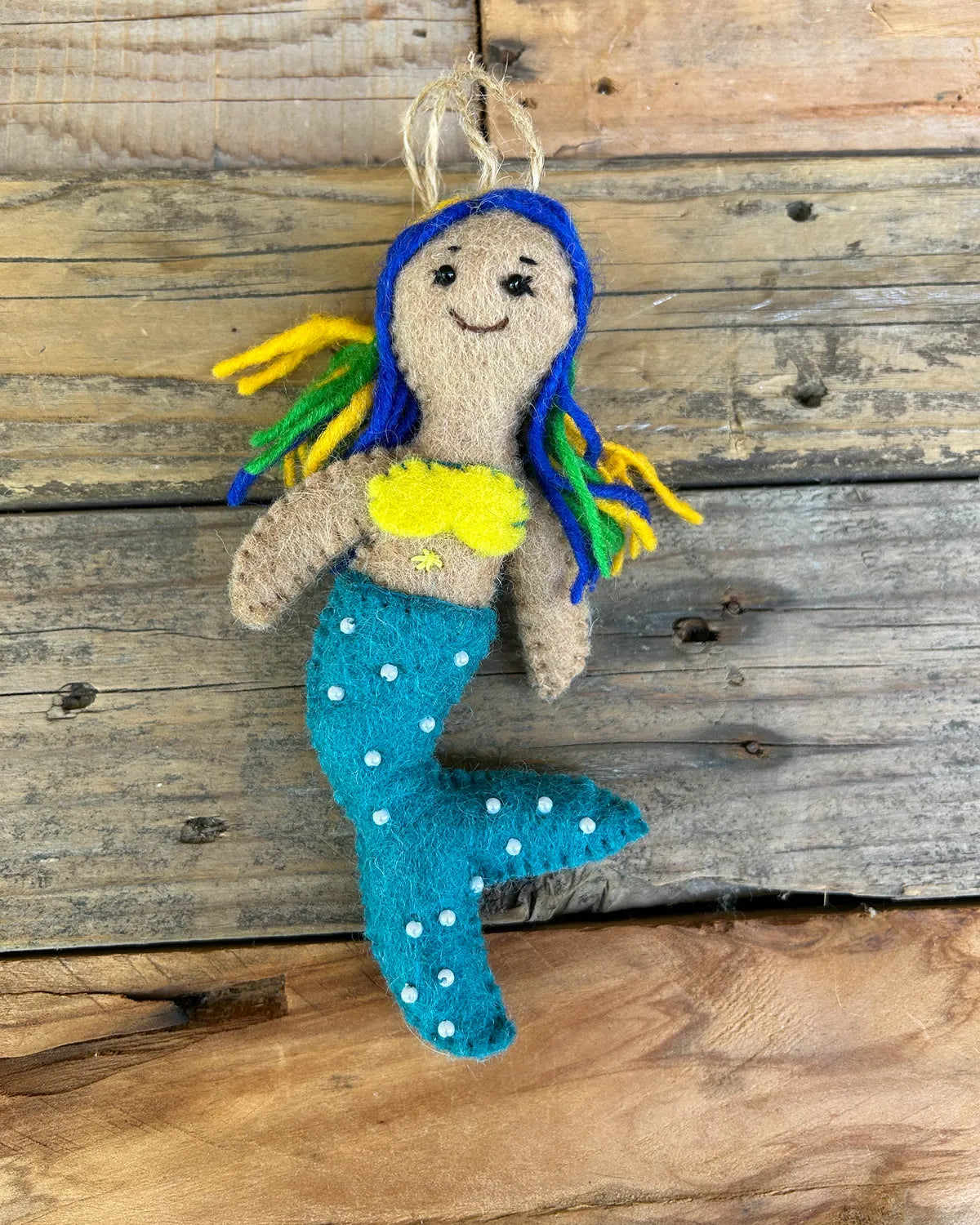 Mermaid figurine with blue hair and tail on a wooden background