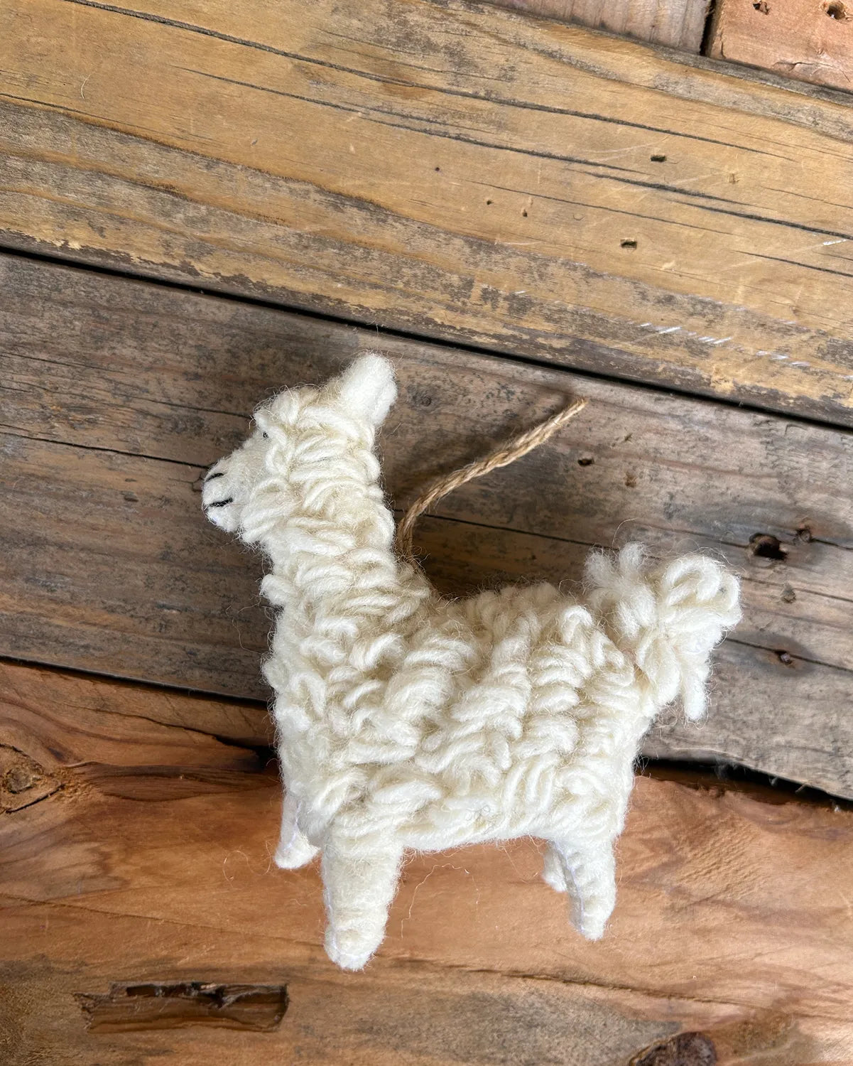 White felted llama toy on a wooden surface