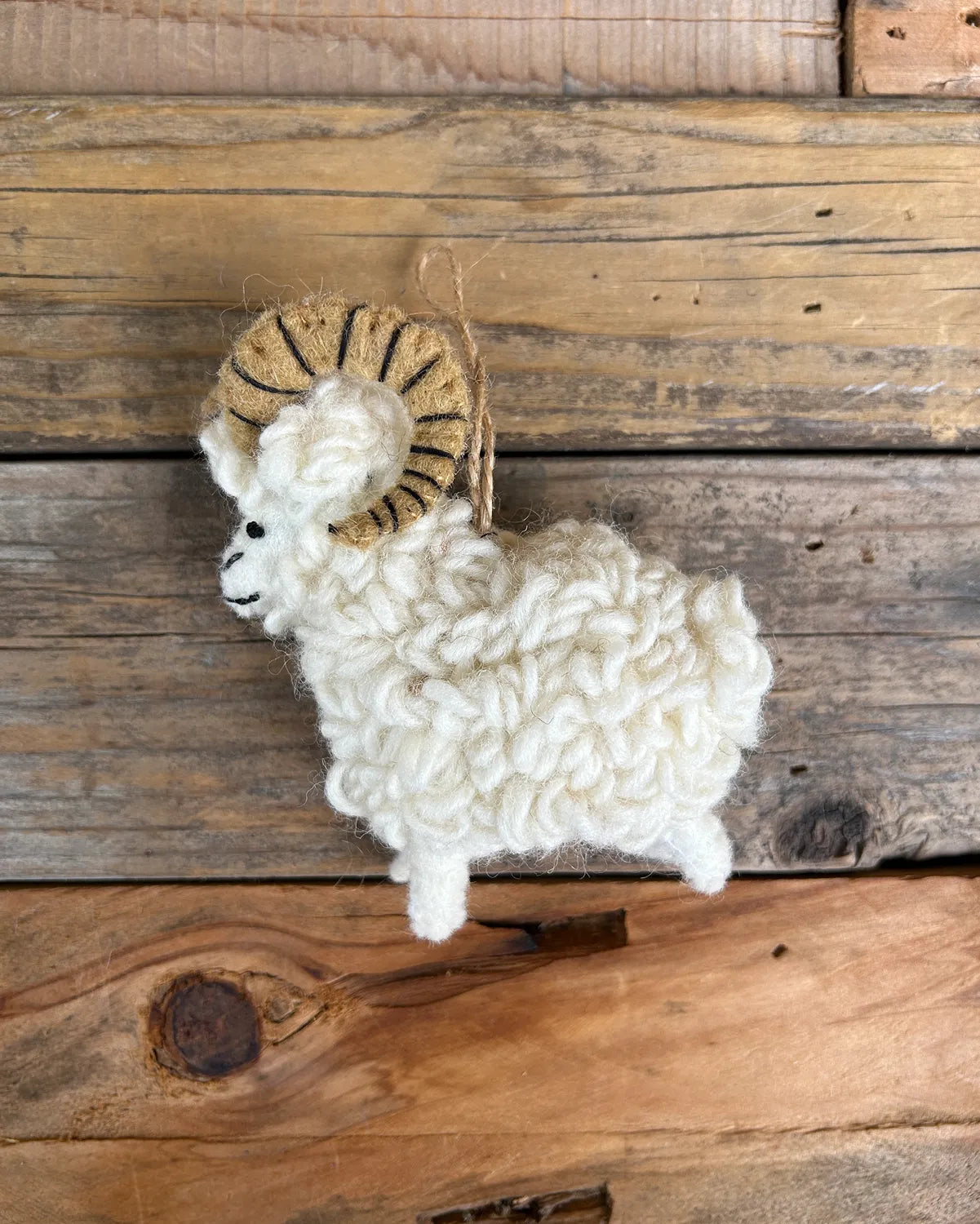Plush toy sheep with ram horns on a wooden background