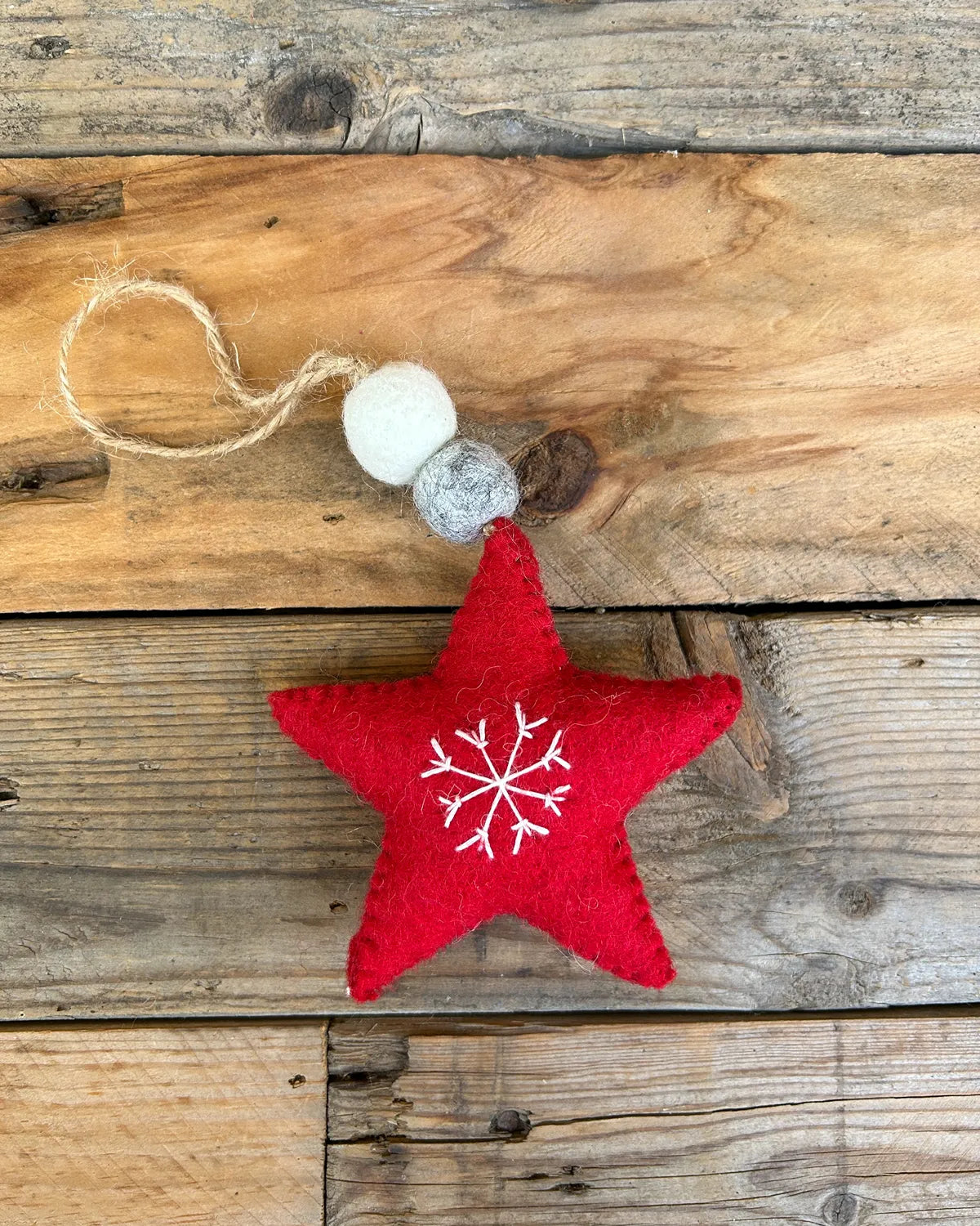 Red star-shaped ornament with a white snowflake design on a wooden surface