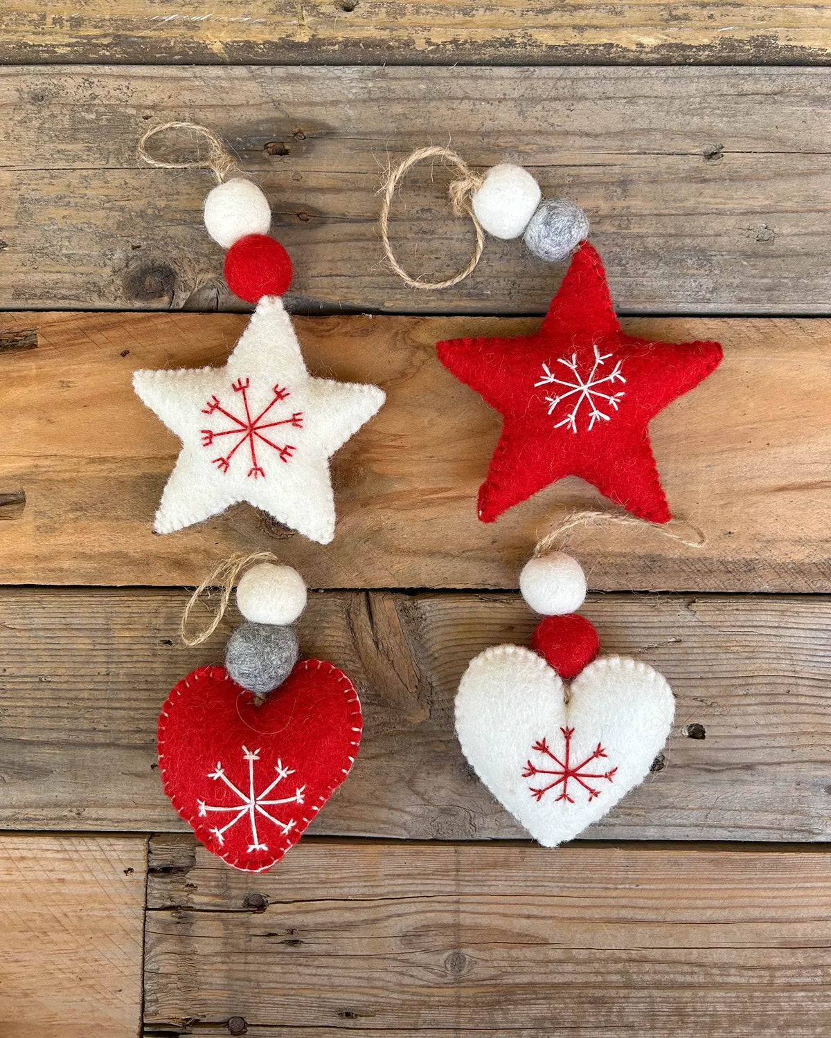 Decorative star and heart ornaments with snowflake designs on a wooden surface