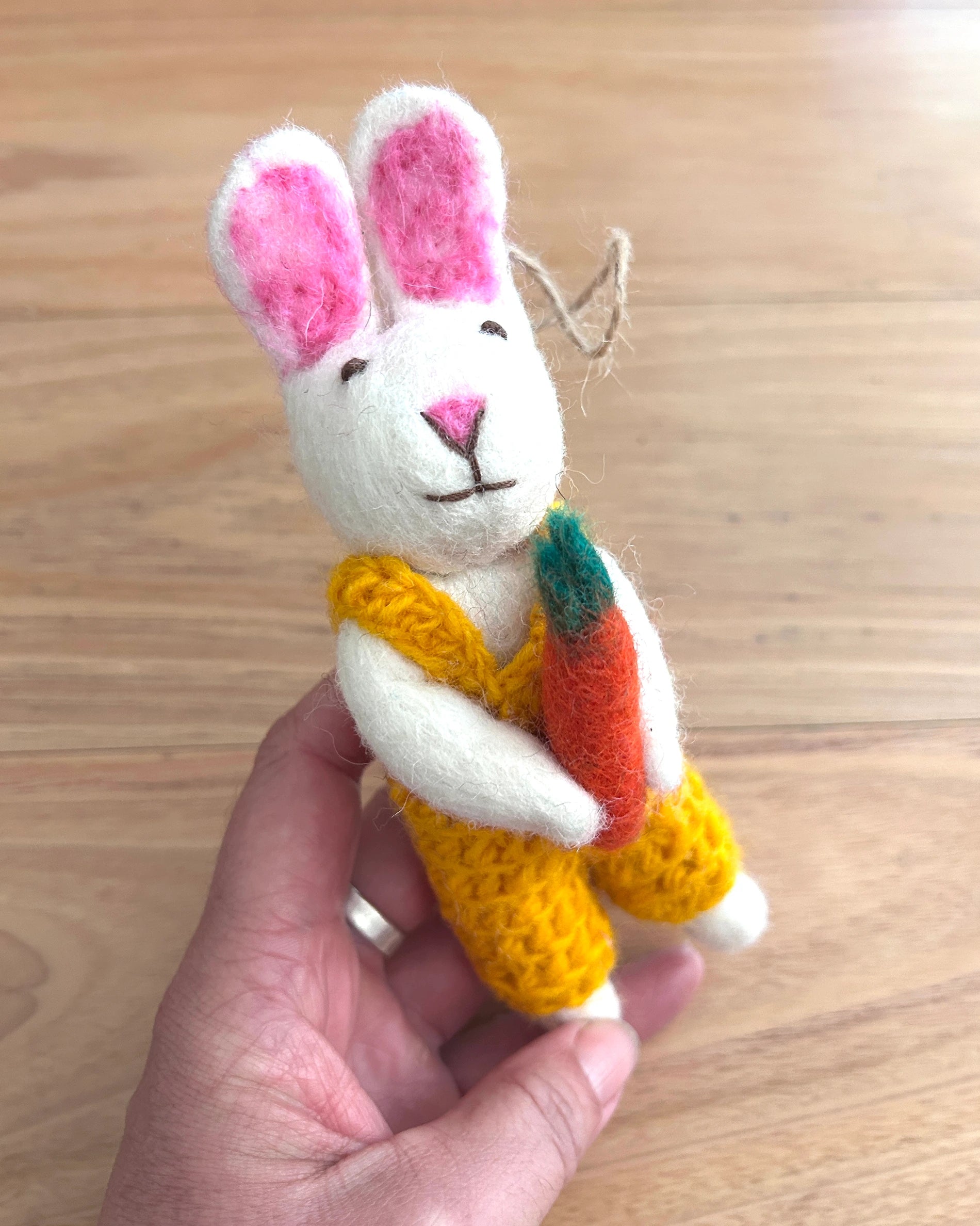 Handmade plush rabbit toy with a carrot on a wooden surface