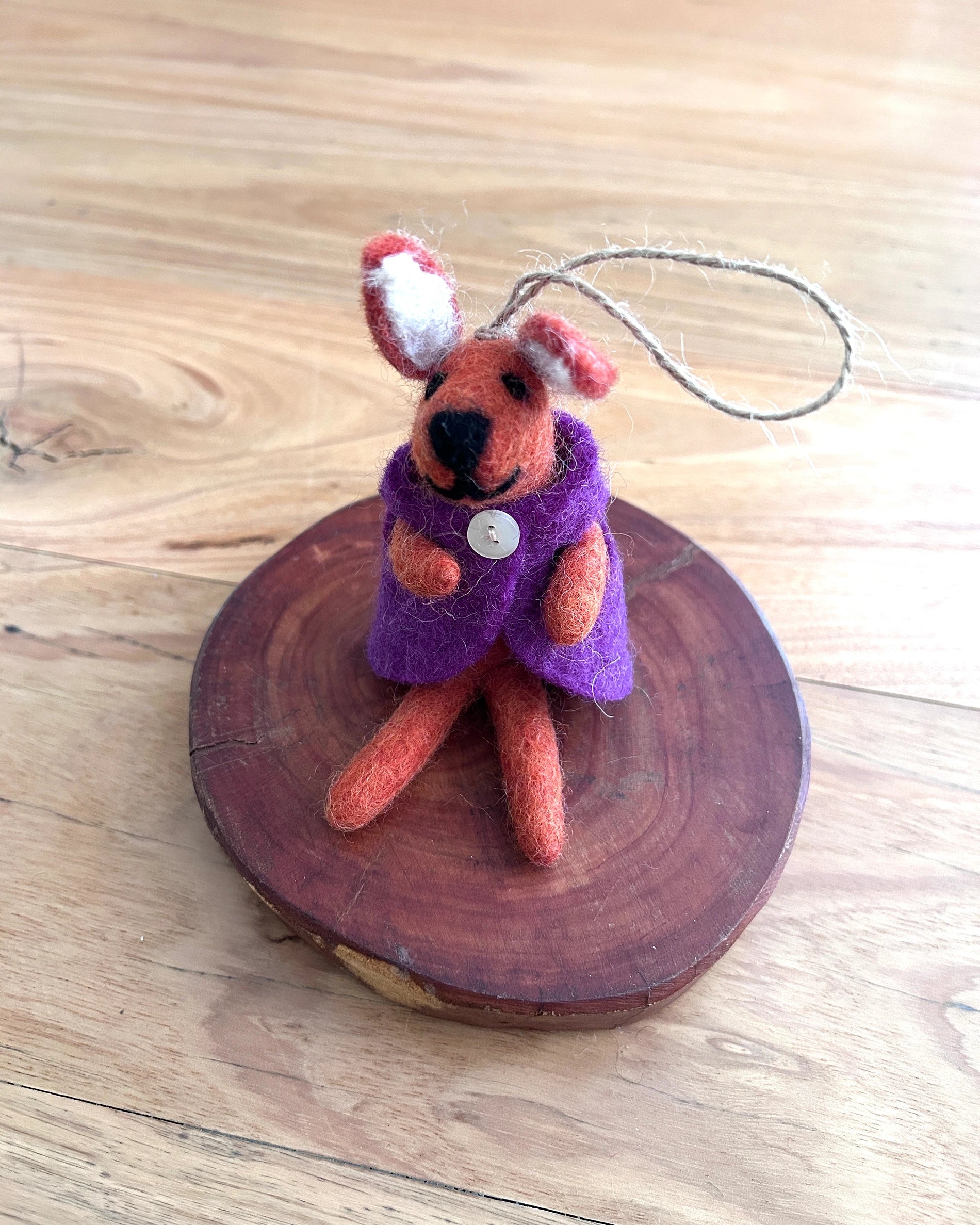 Small felted animal toy with a purple coat on a wooden surface