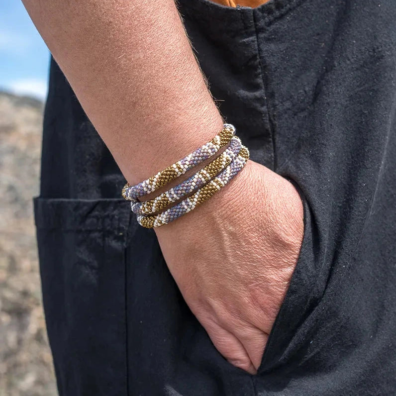 Person wearing multiple bracelets on a wrist with a natural background