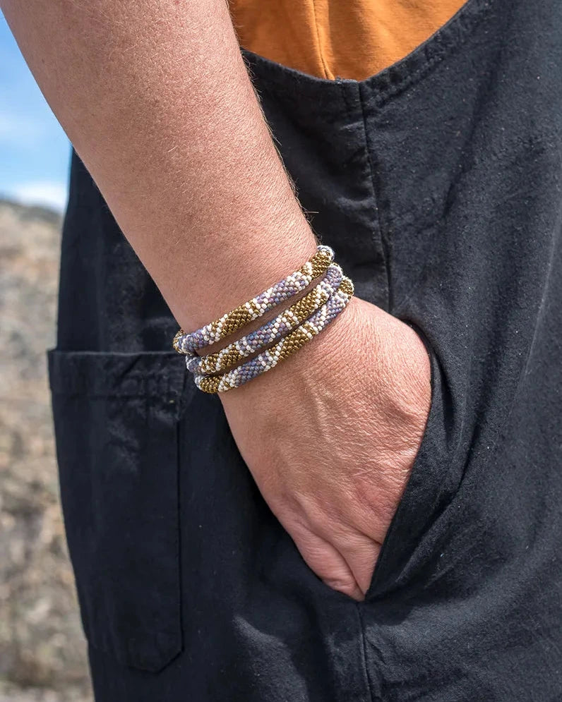 Person wearing multiple bracelets on a wrist with a natural background