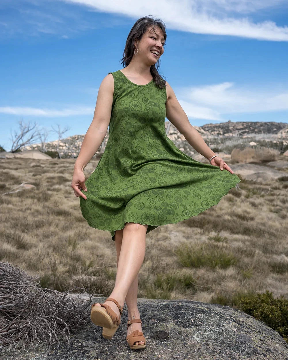Woman in a green dress standing on a rock with a scenic background