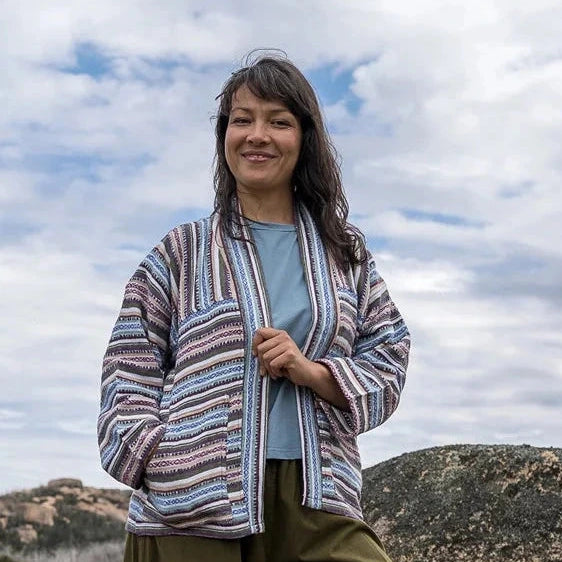Person standing on a rocky outcrop with a striped jacket