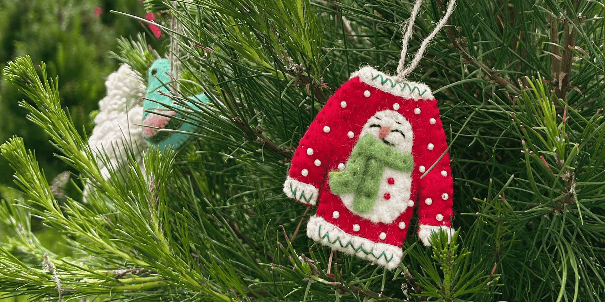 Decorative ornament of a red sweater hanging on a Christmas tree.