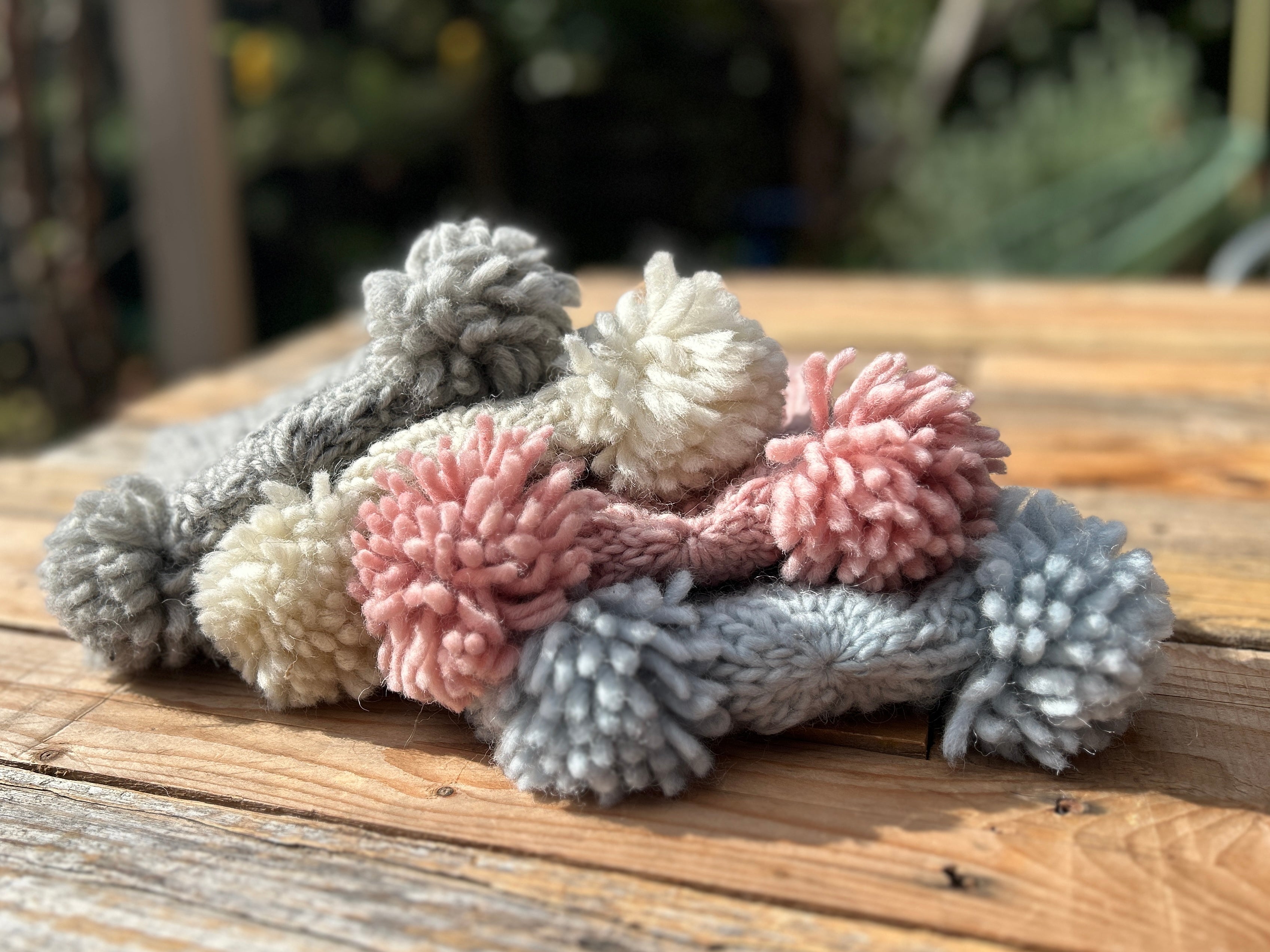 Stack of beanies on a wooden surface with a blurred natural background
