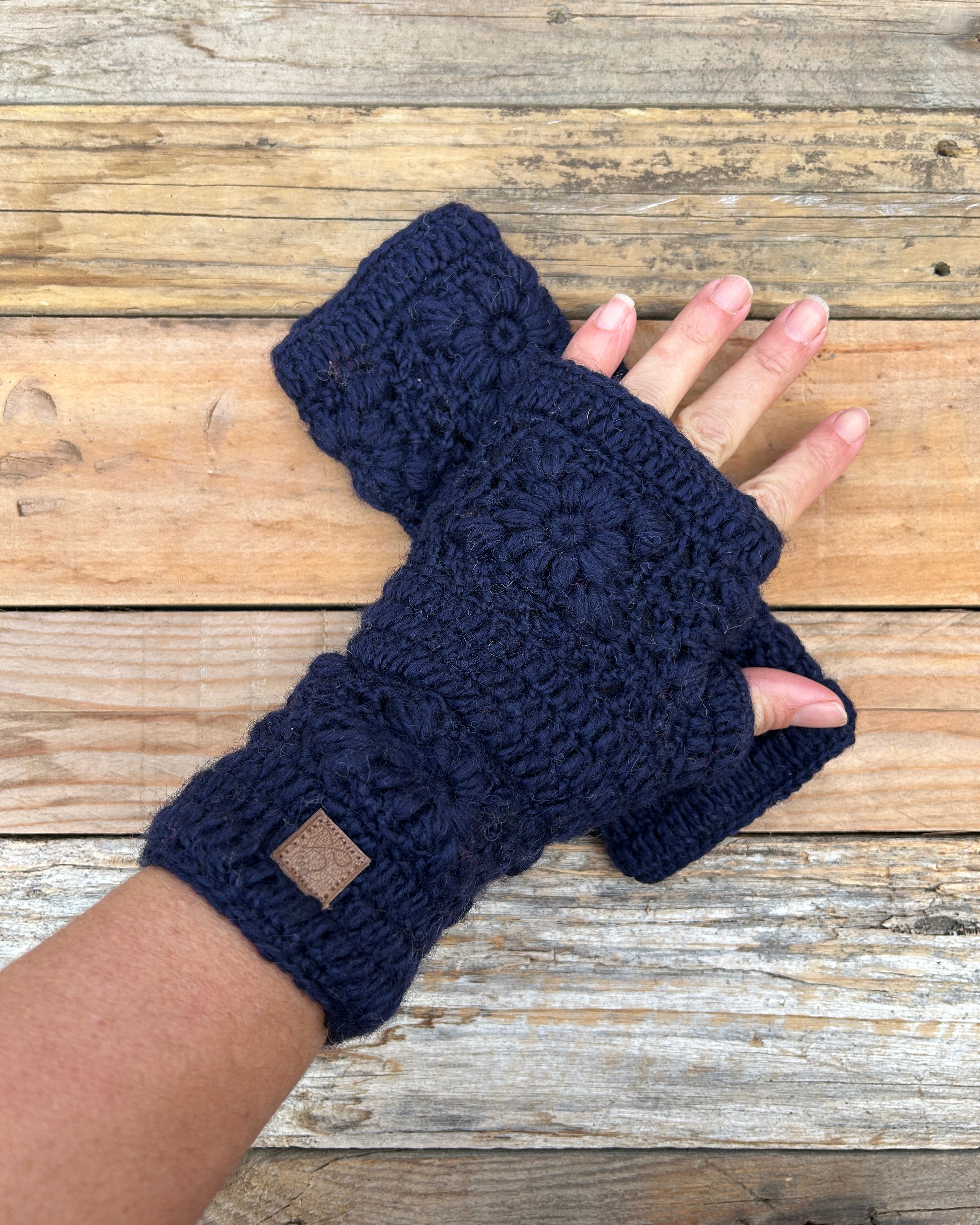Navy blue knitted fingerless gloves on a wooden surface