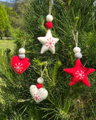 Felt Christmas ornaments shaped like stars and hearts hanging on a tree.