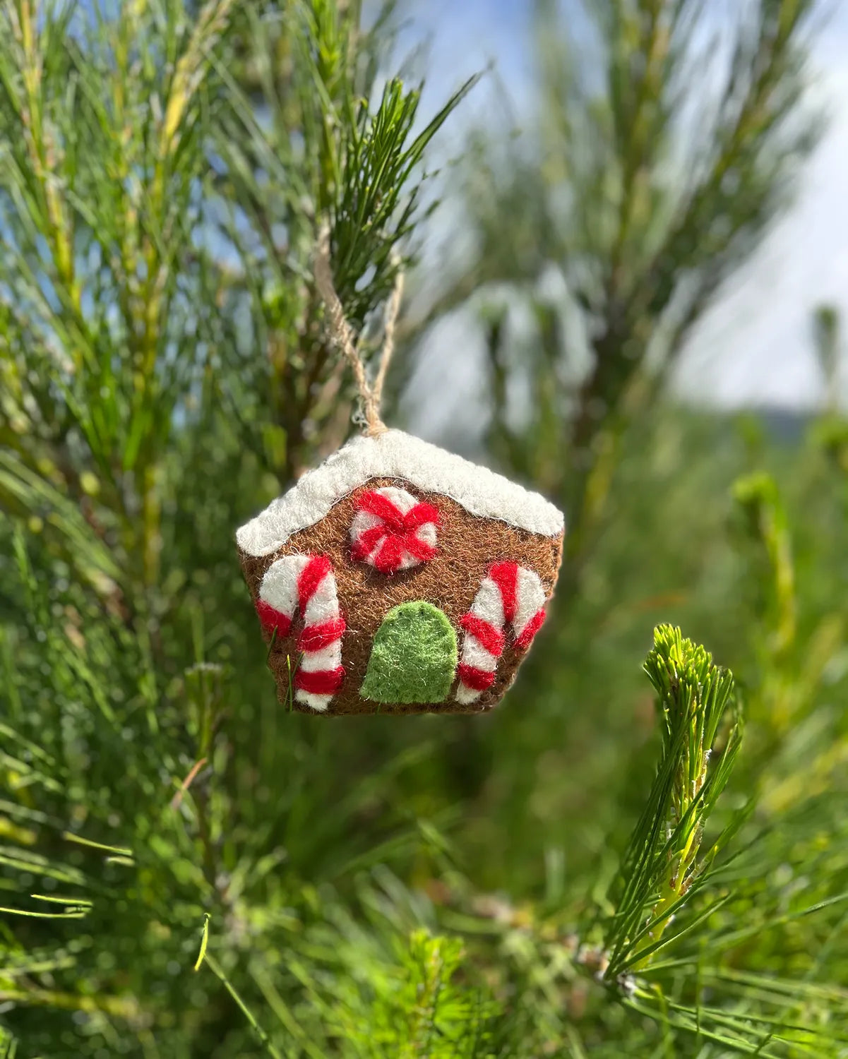 Decorative gingerbread house ornament hanging on a tree