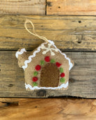 Decorative gingerbread house ornament with red and green details on a wooden background