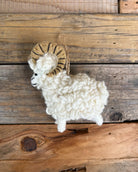 Plush toy sheep with ram horns on a wooden background