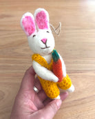 Handmade plush rabbit toy with a carrot on a wooden surface