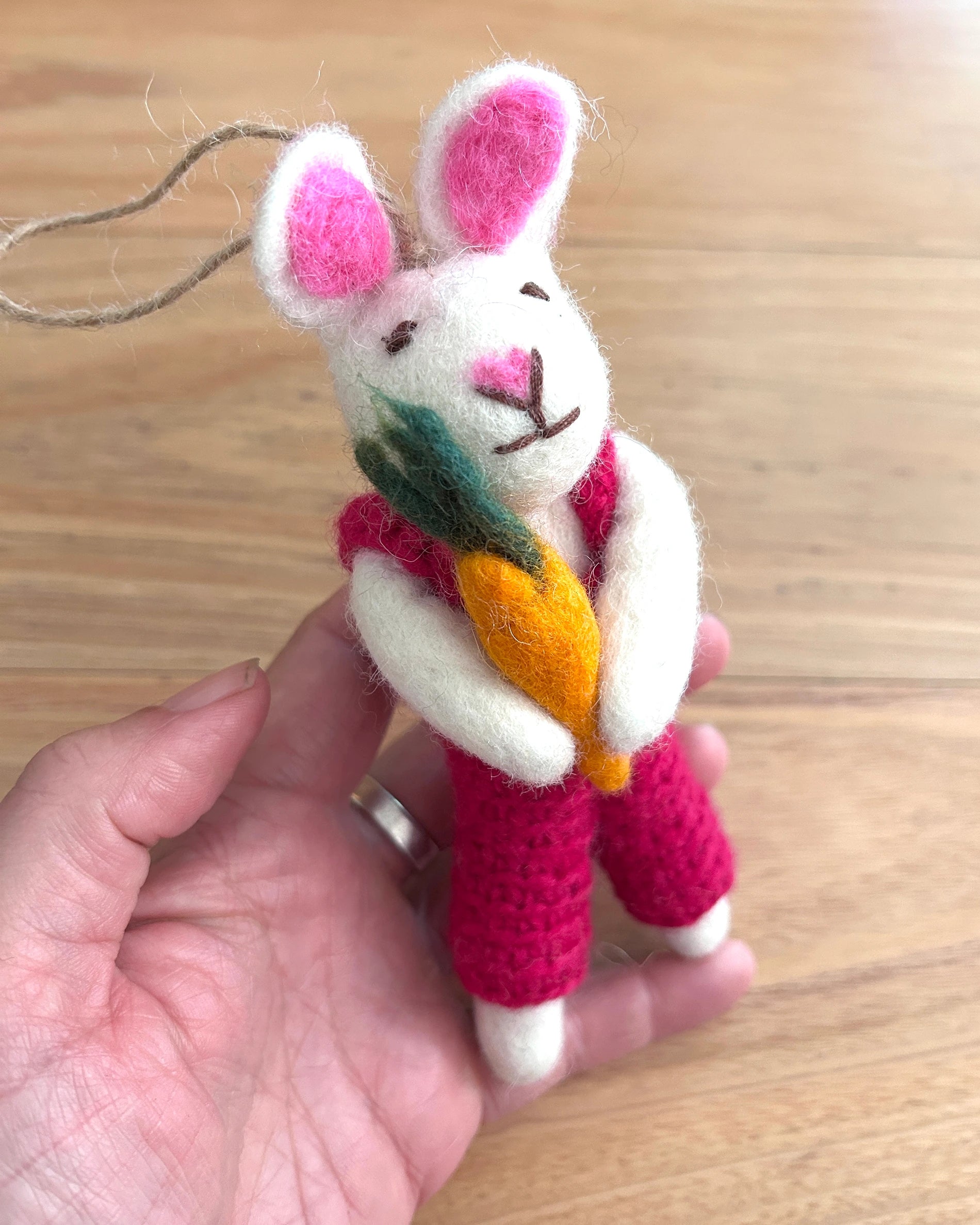 Handmade plush rabbit toy held in a hand on a wooden surface