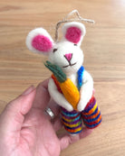 Handmade plush bunny toy with colorful scarf and carrot held by a hand on a wooden surface