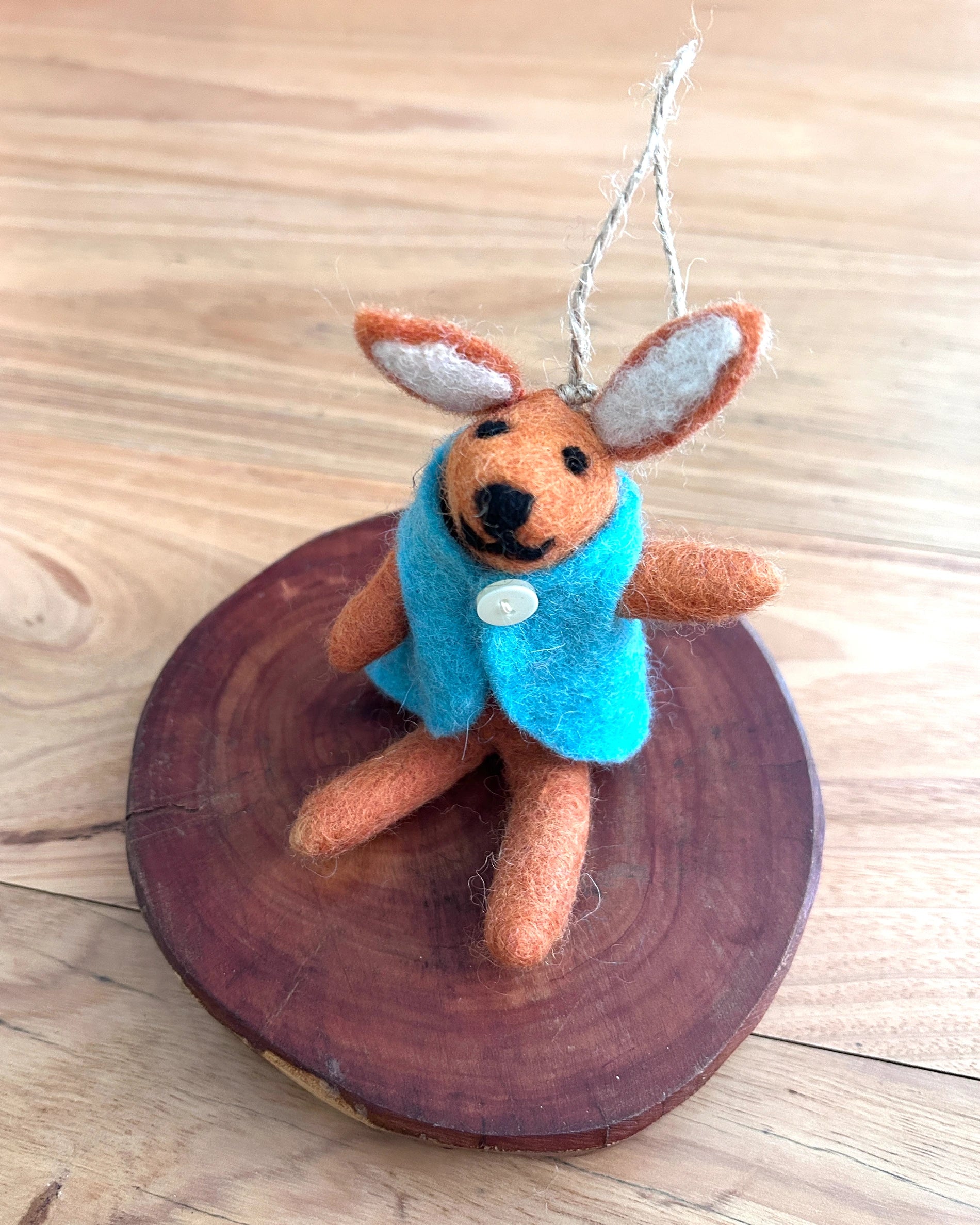 Stuffed bunny toy with a blue sweater on a wooden surface
