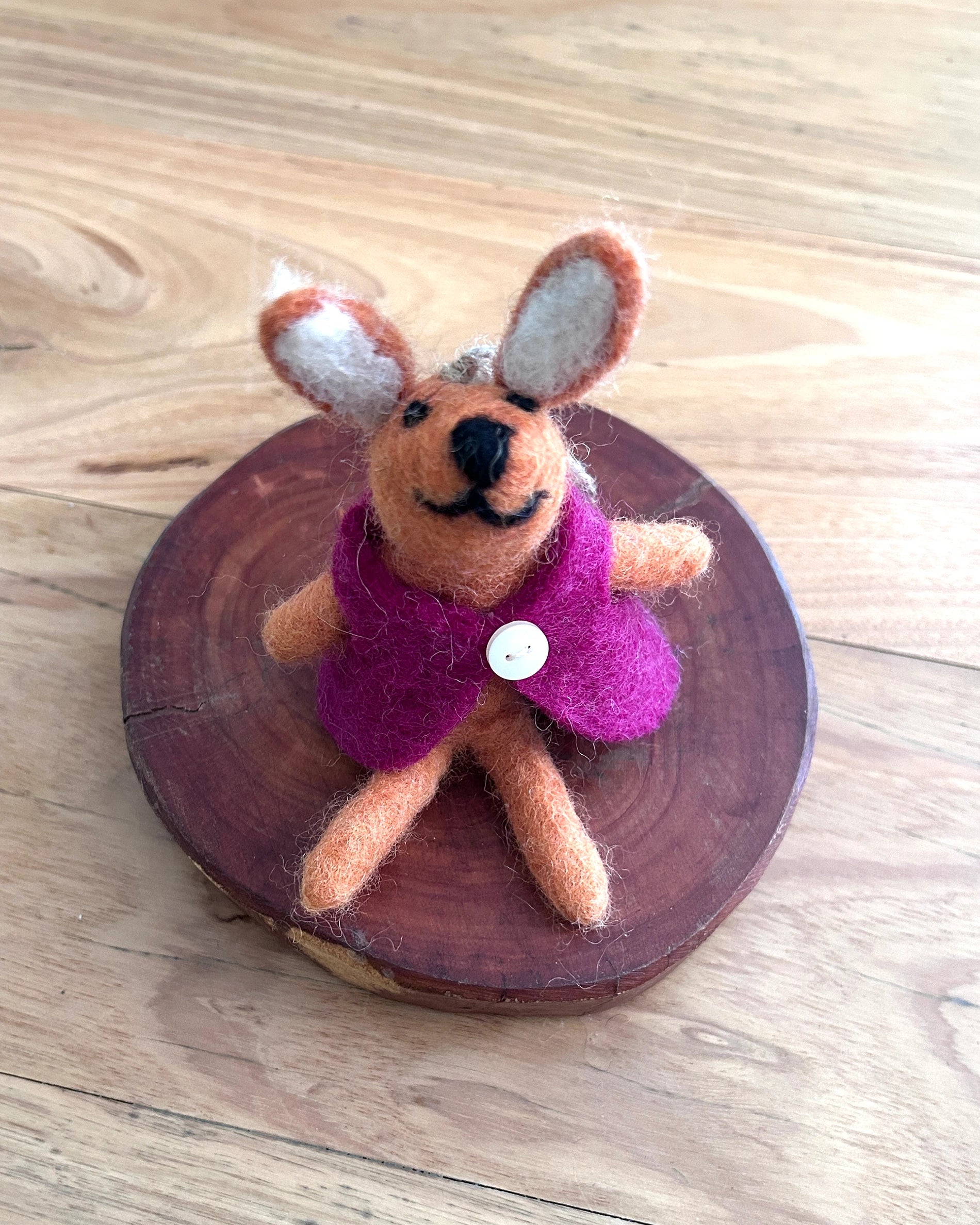 Small felted bunny toy on a wooden disc