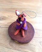 Small felted animal toy with a purple coat on a wooden surface