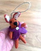 Small orange and purple plush toy held in a hand on a wooden surface