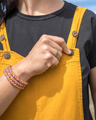 Person wearing yellow overalls and a black shirt with a desert landscape in the background