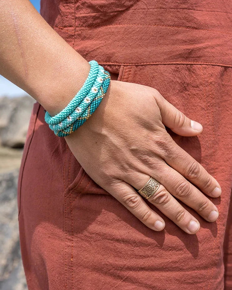 Person wearing a turquoise bracelet and ring with a natural landscape background