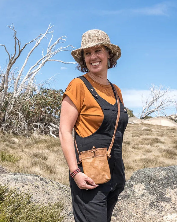 Person standing on a rocky outcrop with a blue sky and trees in the background