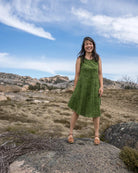 Woman in a green dress standing on a rocky outcrop with a scenic background