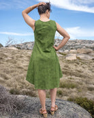 Woman in a green dress standing on a rocky outcrop with a scenic background
