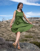 Woman in a green dress standing on a rock with a scenic background