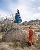 Two women standing on rocks with mountains and blue sky in the background