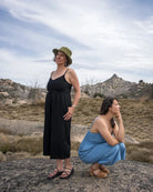 Two women standing on a rocky outcrop with a scenic landscape in the background