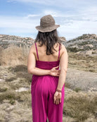Woman in a pink dress and straw hat standing in a desert landscape