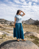 Woman standing on a rock in a desert landscape with mountains in the background