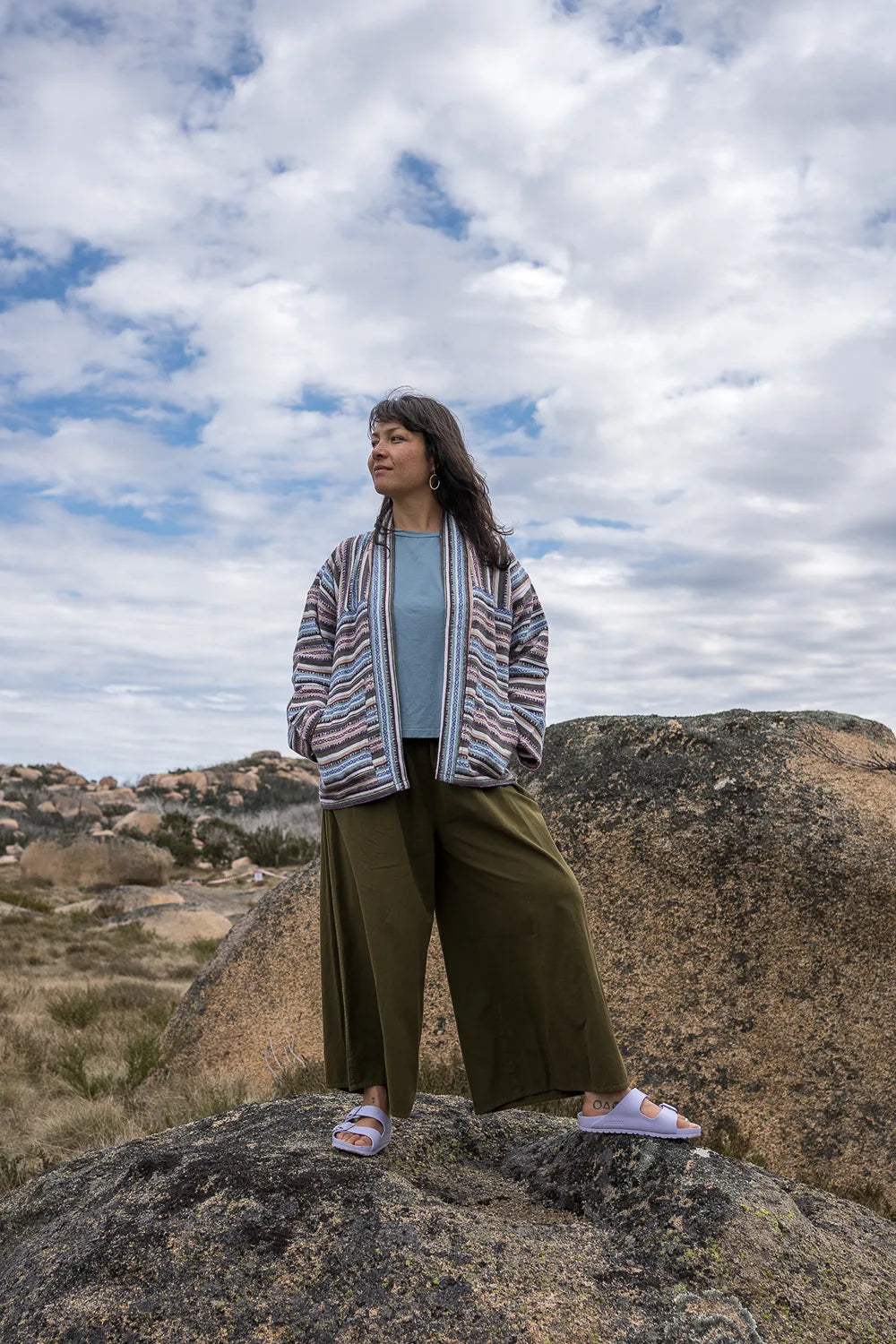 Woman standing on a rocky outcrop with a cloudy sky in the background