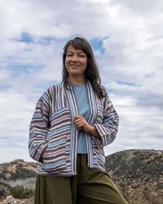 Person standing on a rocky outcrop with a striped jacket